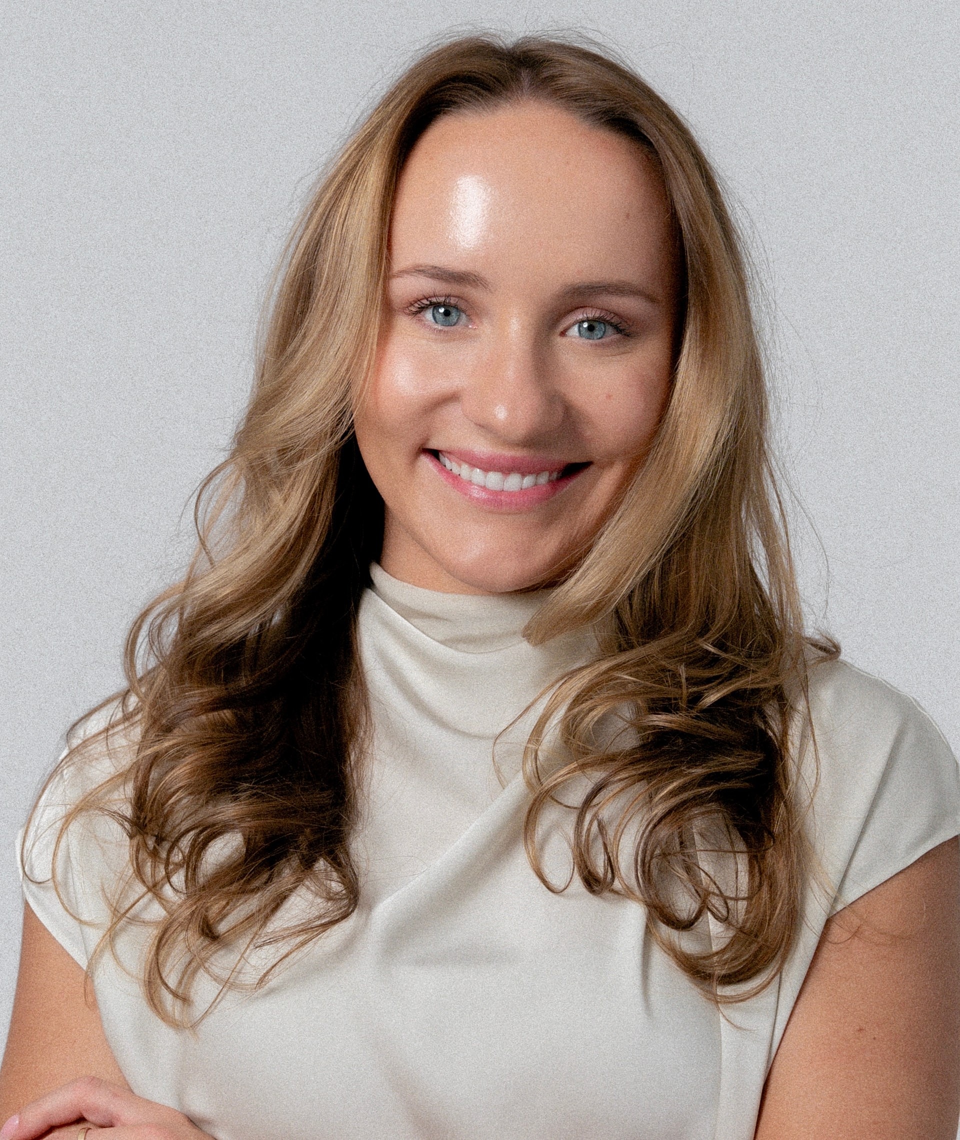Smiling woman with wavy hair and light blouse.