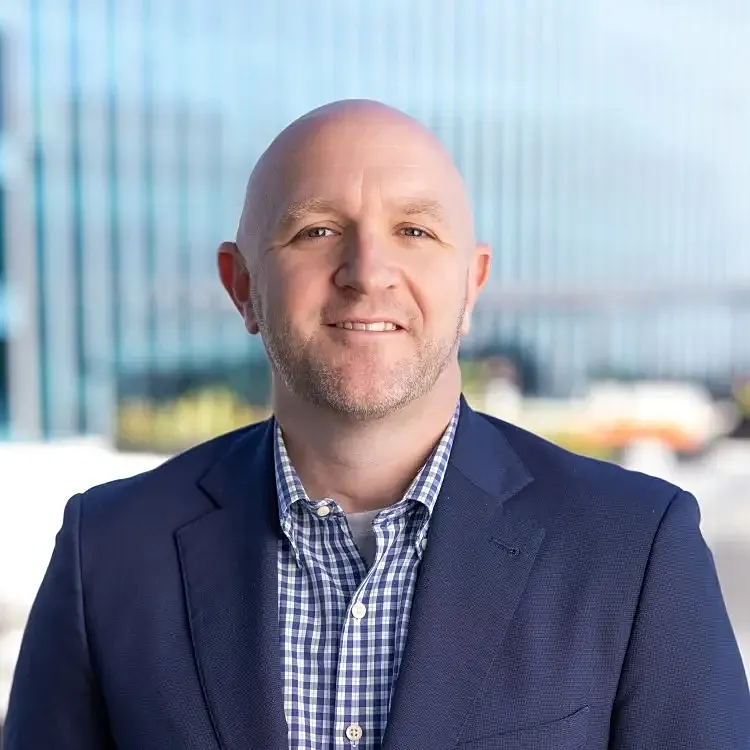 Smiling man in a suit outdoors.