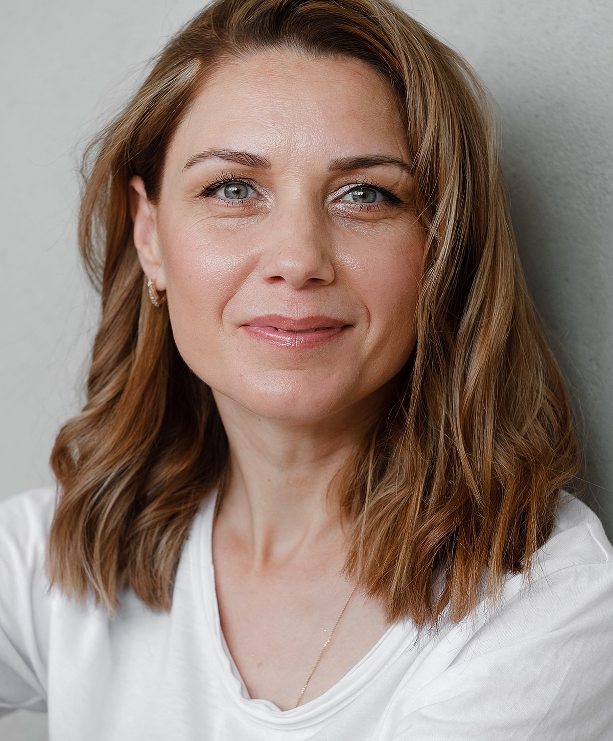 Smiling woman with medium-length hair against wall.