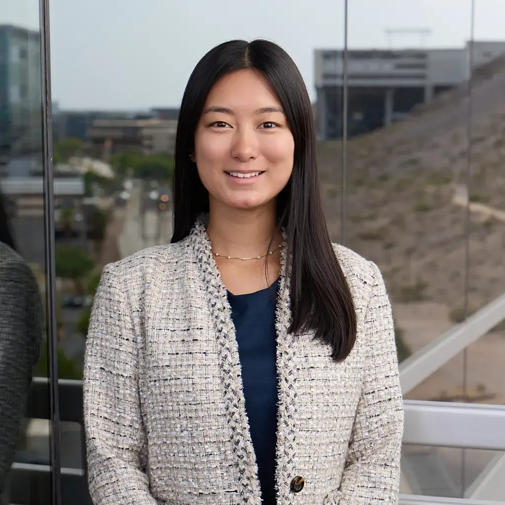 Smiling woman in professional attire with cityscape background.