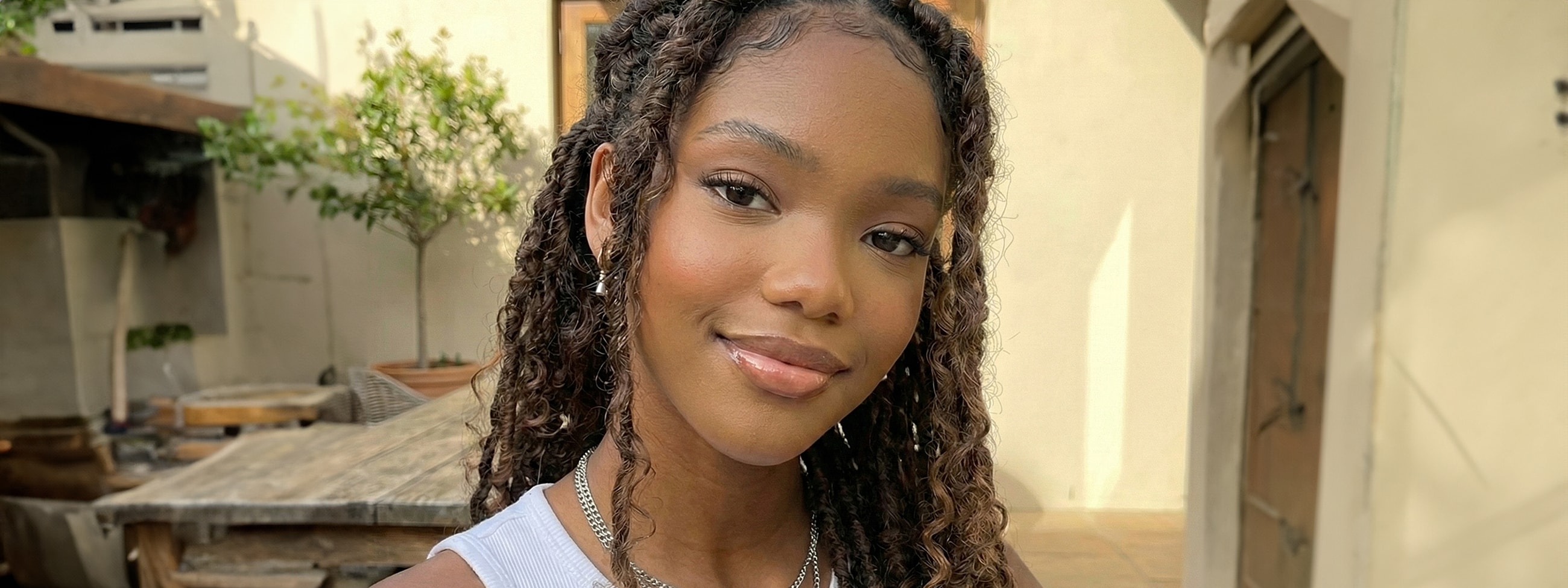 Young woman smiling outdoors with curly hair.