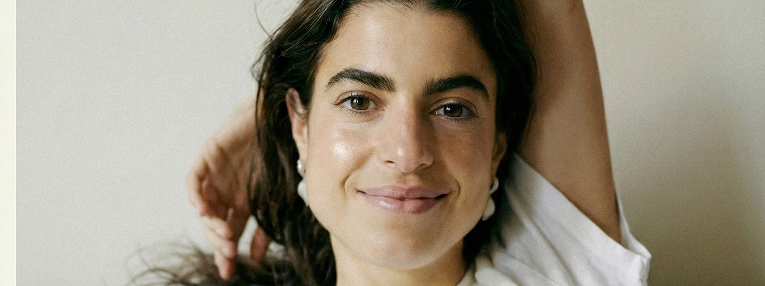 Smiling person with long hair and earrings.