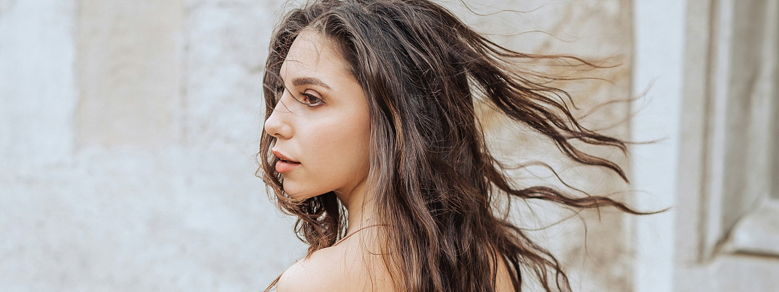 Profile of a woman with flowing hair outdoors.